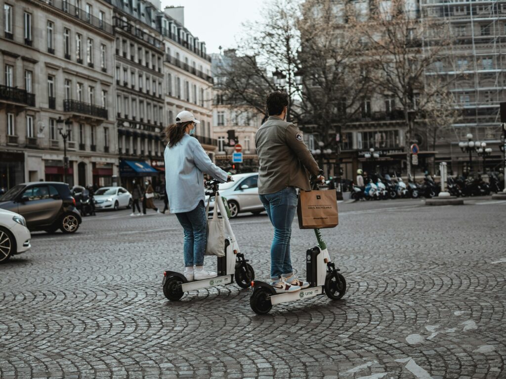 Un homme et une femme sur deux trottinettes électriques dans les rues de Paris