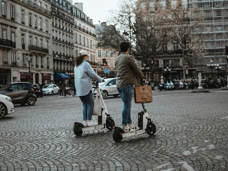 Un homme et une femme sur deux trottinettes électriques dans les rues de Paris