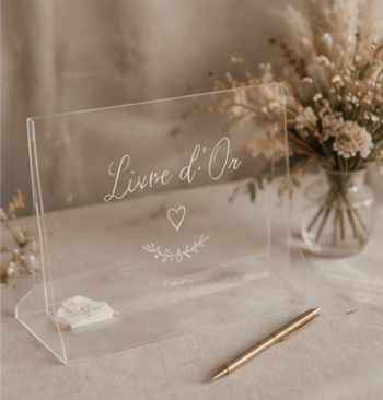 Livre d'or transparent en acrylique avec stylo doré, idéal pour recueillir les messages des invités lors d'un mariage bohème.