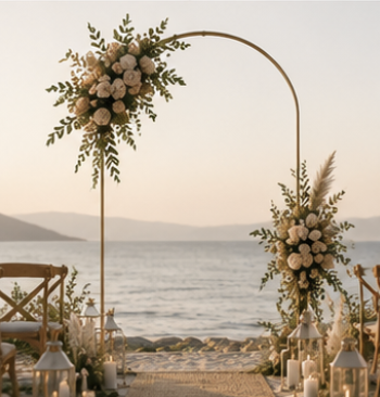 Arche de cérémonie dorée asymétrique avec compositions florales blanches, idéale pour un mariage bohème en bord de mer.