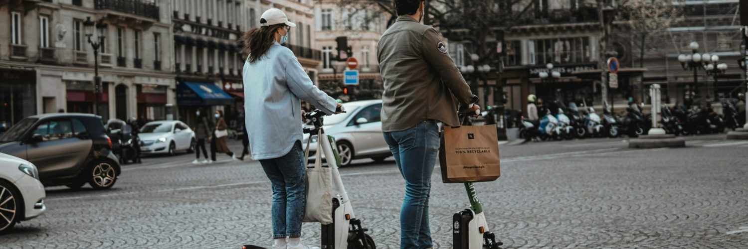 Un homme et une femme sur deux trottinettes électriques dans les rues de Paris